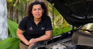 Bárbara Brier apoiada próximo ao motor de um carro