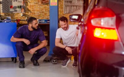 Mecânico e motorista checando componente do carro